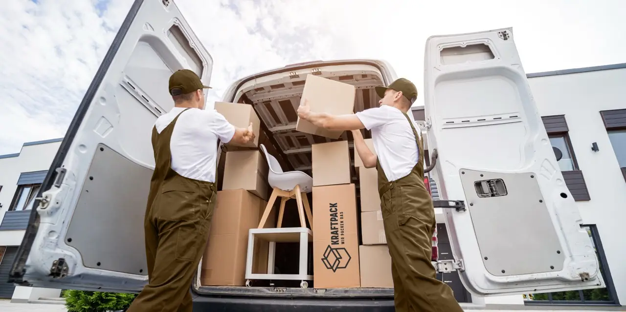 Two workers loading boxes and a chair into a Kraftpack van, illustrating Kleintransporte services in Vienna for efficient and flexible item transport.