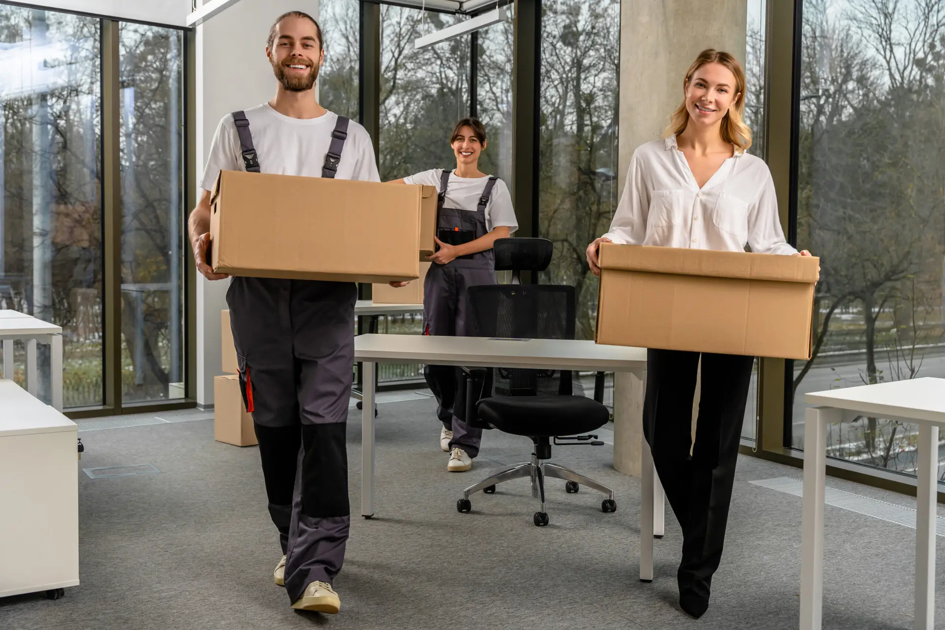 Young colleagues carrying cardboard boxes in a modern office setting, representing Kraftpack's reliable and professional moving services in Vienna.